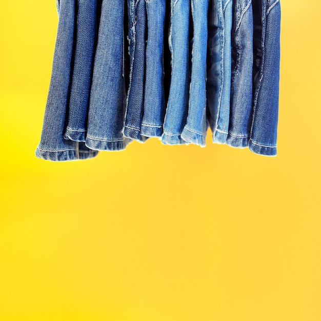 Reihe gehängter Blue Jeans mit gelbem Hintergrund