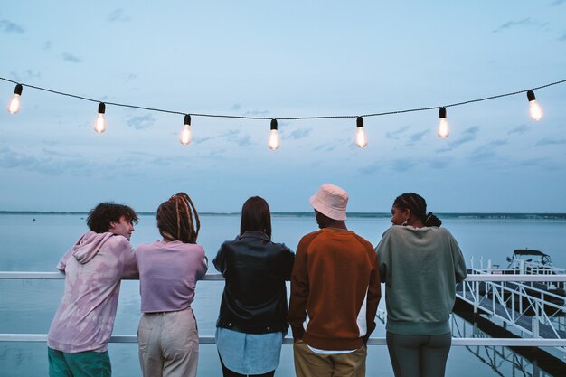 Reihe junger erholsamer Freunde, die auf Pier stehen