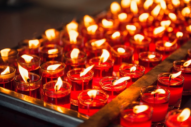 Reihe religiöser roter Votivkerze mit Flamme im Glas im chinesischen Tempel