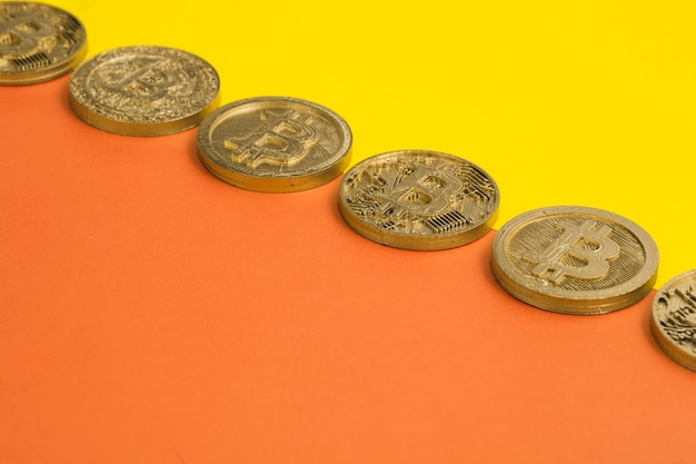 Foto reihe vieler bitcoins über dem gelben und einem orange doppelhintergrund
