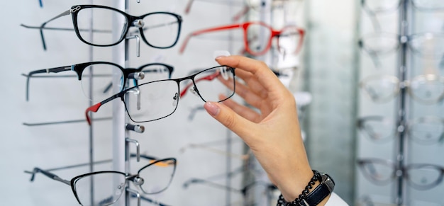 Reihe von Brillen bei einem Optiker Brillengeschäft Stand mit Brille im Optikgeschäft Frauenhand zeigt Brille Präsentieren von Brillen Closeup