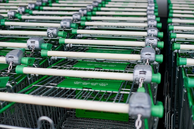 Reihe von geparkten Wagen im Supermarkt. Viele leere grüne Einkaufswagen in Reihe.