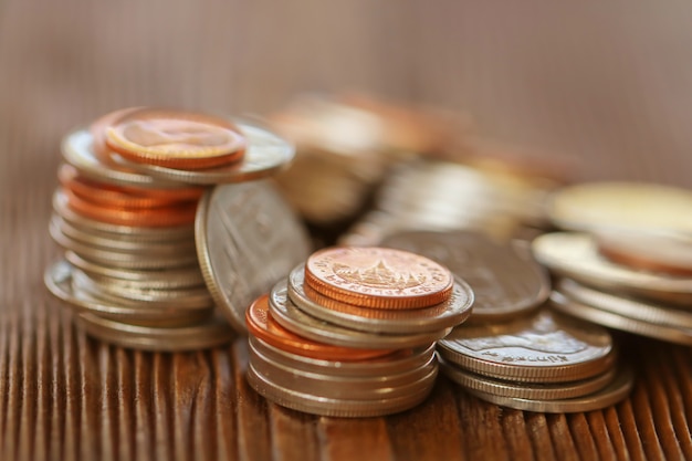 Reihe von Münzen auf hölzernem Hintergrund für Finanz- und Einsparungskonzept, Investition, Wirtschaft, Weichzeichnung