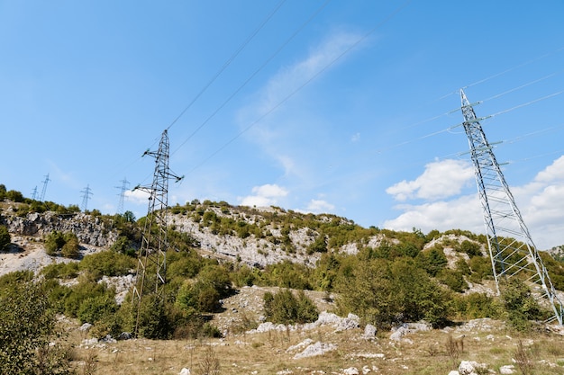 Reihe von Stromleitungen in den Bergen zwischen den Wäldern