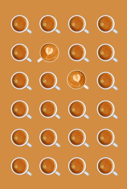 Reihen von Espressokaffees mit herzförmigen Latte Art Cappuccinos auf aprikosenbraunem Hintergrund