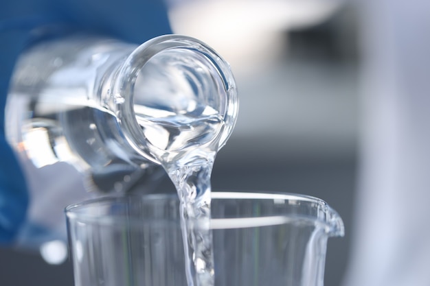 Reines Wasser wird aus der Glasflasche in Glas gegossen
