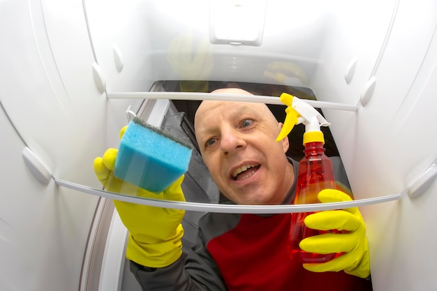 Reinigen und waschen Sie das Innere des Kühlschranks mit einem Reinigungsspray und einem Schwamm. Professioneller Service zur Desinfektion von Küchengeräten zur Lebensmittelkonservierung