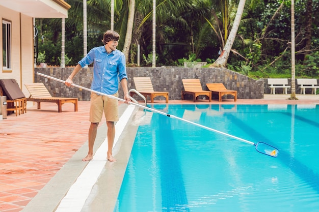 Reiniger des Schwimmbades. Mann in blauem Hemd mit Reinigungsgerät für Schwimmbäder, sonnig