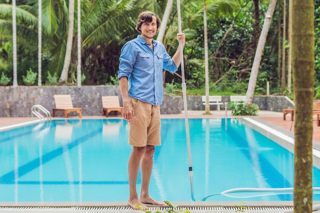 Reiniger des Schwimmbadmannes in einem blauen Hemd mit Reinigungsausrüstung für sonnige Schwimmbäder