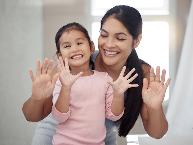 Reinigung der Hände und Waschen mit Mutter und Tochter, die sich in einem Badezimmer zu Hause verbinden, lächeln und sich zusammen entspannen Hygieneschutz und Porträt eines Mädchens, das sich nach dem Erlernen einer gesunden Gewohnheit glücklich fühlt