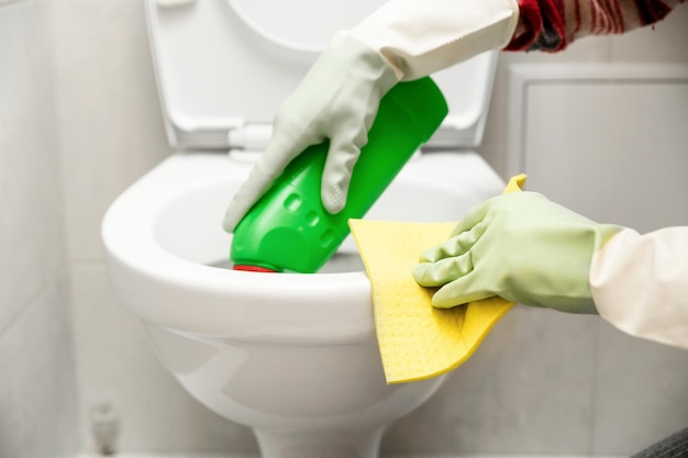 Reinigung der Toilettennahaufnahme Hände, die einen Lappen und ein Reinigungsmittel zum Reinigen halten