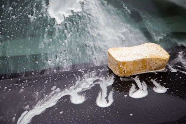 Foto reinigung von autos mit mit schaum bedeckten chemischen reinigungsmitteln während der autowascherei