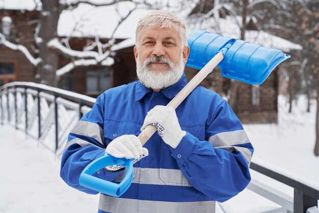 Reinigungsmittel im Arbeitsoverall mit Schaufel am Winteryard.