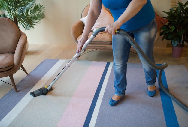 Reinigungsservice-Konzept. Sauberer Teppich der Frau mit Staubsauger