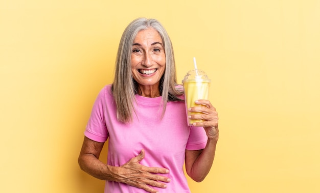 Reírse a carcajadas de una broma divertida, sentirse feliz y alegre, divertirse y tomar un batido.