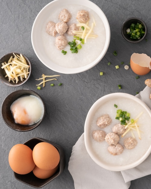 Reis Congee mit gehacktem Schweinefleisch in der weißen Schüssel. Schüssel Reisbrei mit weichem gekochtem Ei. Asiatisches Frühstück