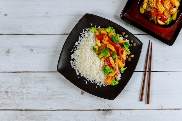 Reis mit Stirfischrogenhuhn und -gemüse auf Platte des schwarzen Quadrats. Chinesische Küche.