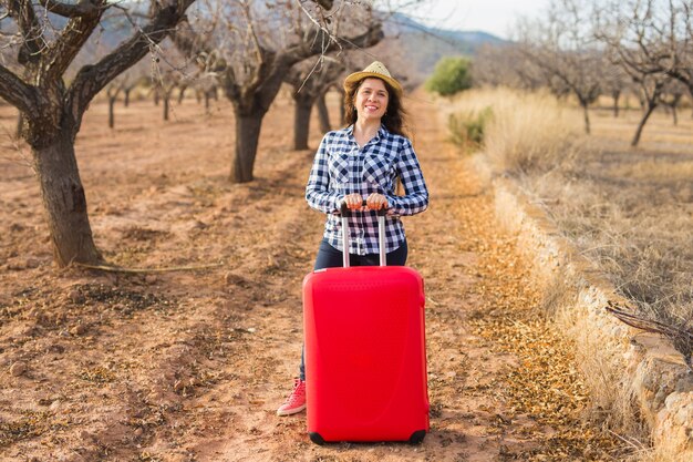 Reise-, Sommer- und Menschenkonzept. Frau mit rotem Koffer im Hut