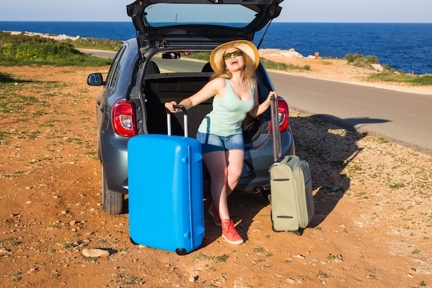 Reise-, Sommerferien- und Urlaubskonzept - Junge Frau mit Koffern auf Autofahrt.