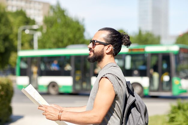 reise-, tourismus-, rucksack- und personenkonzept - mann, der mit rucksack und karte in der stadt reist und nach standort sucht