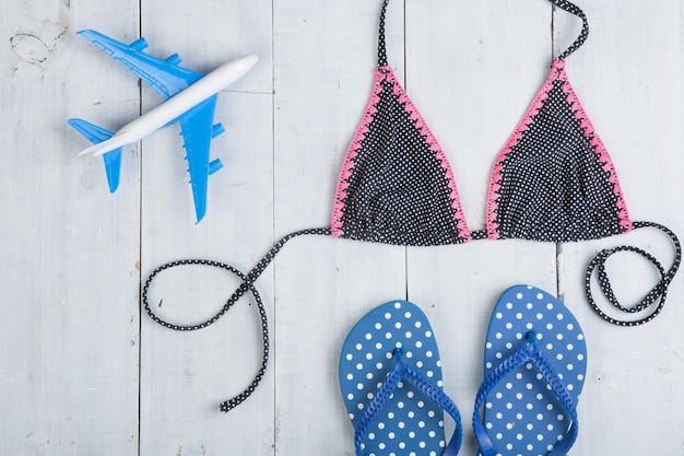 Reise- und Urlaubskonzeptmodell eines Flugzeugmode-Badeanzugs mit Flip-Flops in Polka Dots