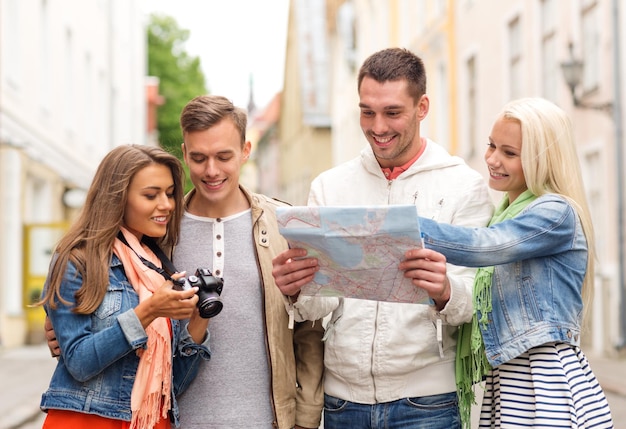 reise-, urlaubs-, technologie- und freundschaftskonzept - gruppe lächelnder freunde mit karte und fotokamera, die die stadt erkunden