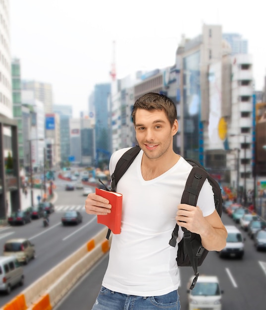 reise-, urlaubs- und bildungskonzept - reisender student mit rucksack und buch