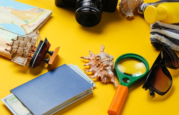 Reiseaccessoires und Retro-Kamera auf gelbem Hintergrund. Sommerstrandhintergrund. Urlaubskonzept