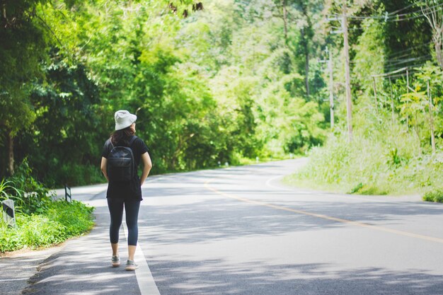 Reisefrau mit Hut und Rucksack gehend auf eine Straße bei Chiangmai