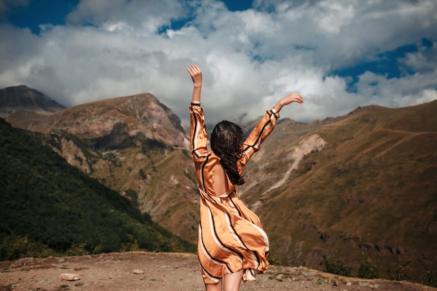 Reisefrauentourist, der gegen den Hintergrund der Berge und des bewölkten Himmels aufwirft.