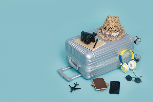 Reisegepäck mit Pass, Kamera, Hut, Brieftasche, Flugzeugspielzeug und Smartphone lokalisiert auf blauem Hintergrund mit Kopienraum