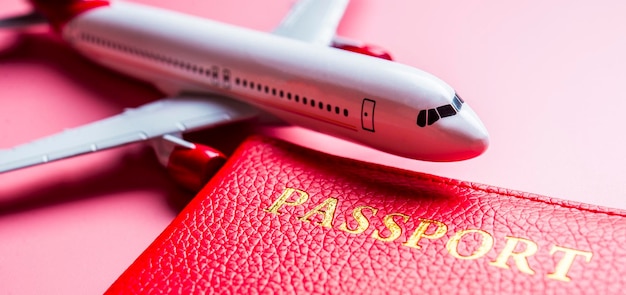 Reisekonzept für den warmen Sommer Flugzeugmodell auf rosa Hintergrund mit Reisepass