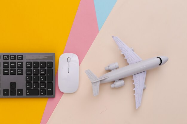 Reisekonzept. PC-Tastatur und Flugzeug auf farbigem Tisch