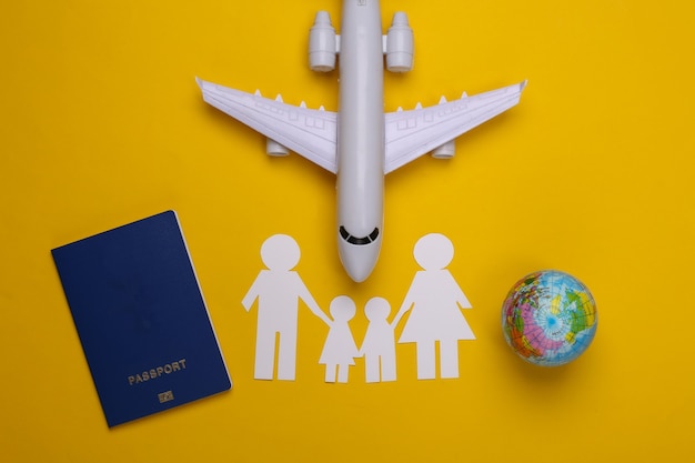 Reisen oder Familieneinwanderung. Papierfamilie zusammen, Flugzeug, Globus und Pass auf Gelb.