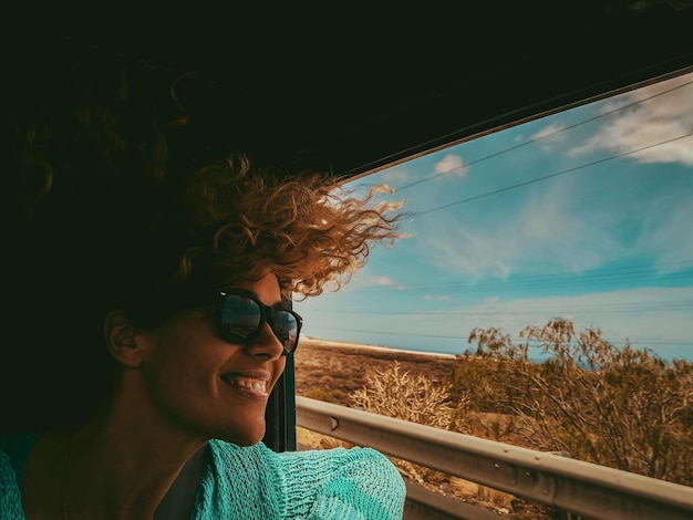 Reisen Sie mit dem Bild der Autofahrer Glückliche Frau, die lächelt und die Aussicht außerhalb des Fahrzeugs genießt