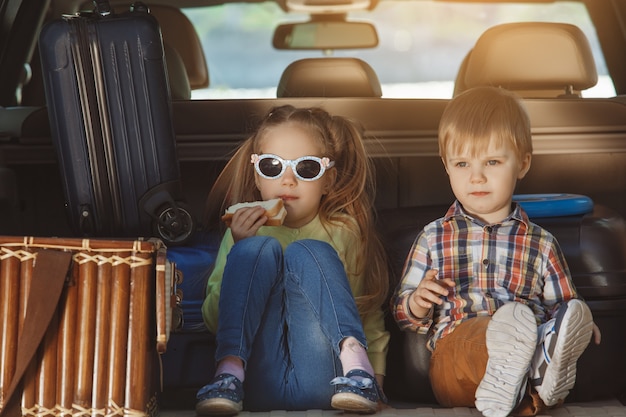 Reisen Sie mit der Autofamilie zusammen, Bruder und Schwester sitzen in einem Kofferraum