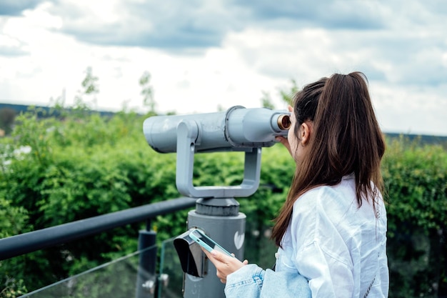 Reisen Sie Sightseeing-Touristin der jungen Frau, die im Fernglas-Teleskop schaut