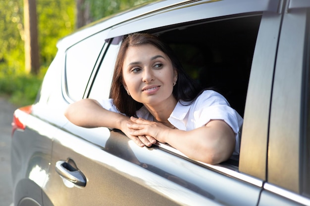 Reisen Urlaub Eine junge schöne Frau sitzt in einem Auto und lächelt in die Ferne Lifestyle