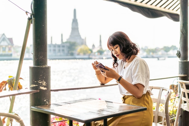 Reisende der asiatischen Frau, die ihr Telefon im Café benutzt