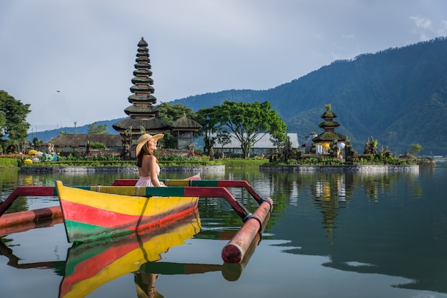 Foto reisende der jungen frau, die auf einem hölzernen boot bei pura ulun danu bratan paddelt