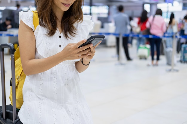 Foto reisende der jungen frau, die ihr smartphone verwendet, um flug im flughafen zu überprüfen