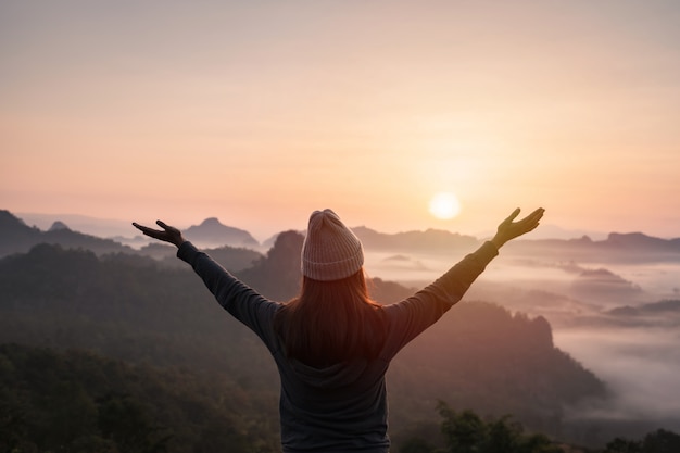 Reisende der jungen Frau, die Meer des Nebels und des Sonnenuntergangs über dem Berg betrachtet