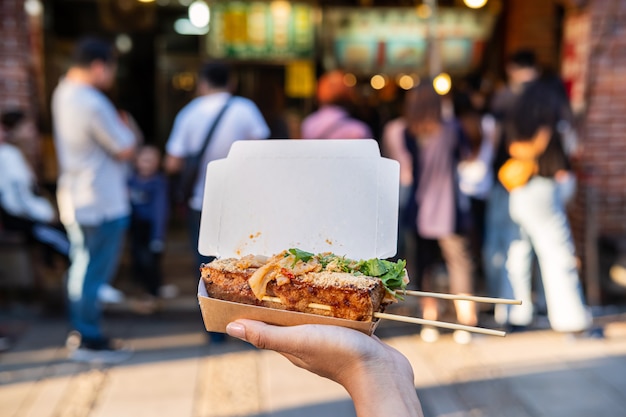 Reisende der jungen Frau, die stinkenden Tofu am taiwanesischen Straßenessen, Reiselebensstilkonzept hält