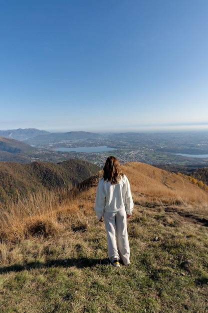 Reisende frau in weiß gekleidet auf der bergspitze, die die landschaft von lago di como italien bewundert