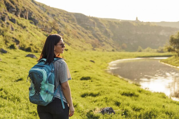 Reisende Frau mit Rucksack an der grünen Wiese der Natur