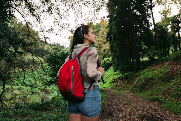 Reisende Frau mit Rucksack, der im Wald geht