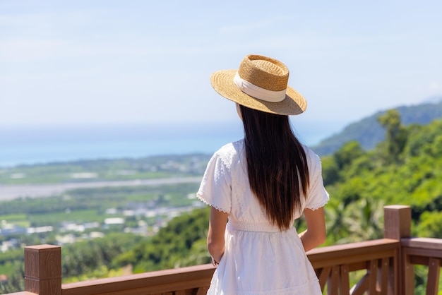 Reisende Frau steht auf der Terrasse und schaut sich die Landschaft an