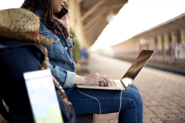 Reisende Frauen auf Reisen haben Reisetaschen, Hut, Sonnenbrille und Karten mit Tablets im Bahnhof.