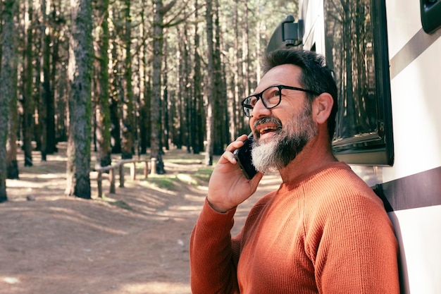 Reisende Mann steht vor einem modernen Wohnwagen Campingwagen und genießt das Ziel in der Natur Wald Menschen und Fahrzeug Reisen Wohnwagen Lebensstil Vanlife Alternatives Zuhause und Urlaub Urlauber