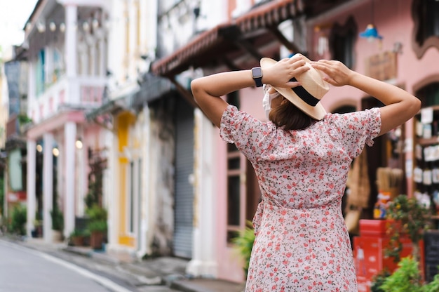 Reisende mit Maske, die auf der Straße in der Altstadt von Phuket spazieren gehen, mit Gebäude der chinesisch-portugiesischen Architektur in der Altstadt von Phuket Phuket Thailand Reisekonzept und Sommerreise